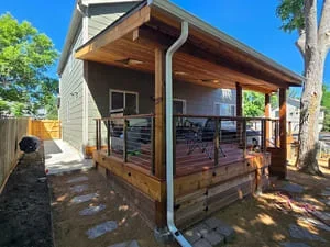 Custom wood deck with covered patio structure and metal railings in Littleton backyard