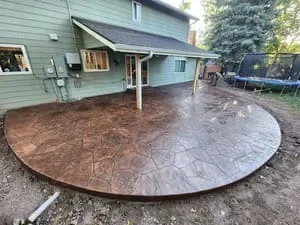 Circular stamped concrete patio with brown finish in residential backyard
