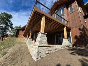Stacked stone foundation with yellow support posts around residential home addition